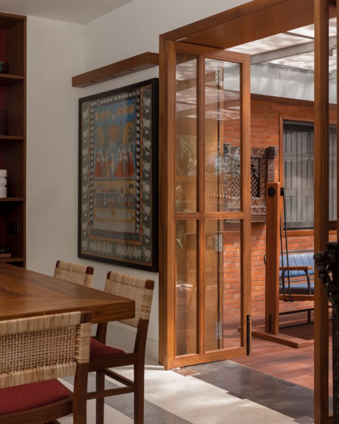 Teak wood and glass doors separate the dining area from the backyard; Photography by Prachi Khasgiwala