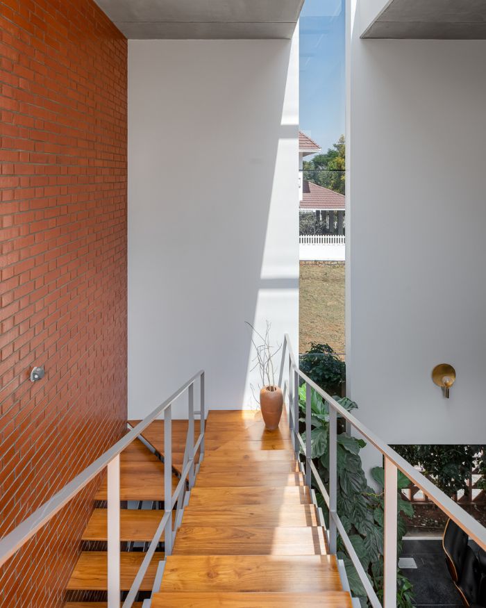 A vertical slit window casts dynamic shadows across the brick surfaces throughout the day; Photography by Arjun Krishna