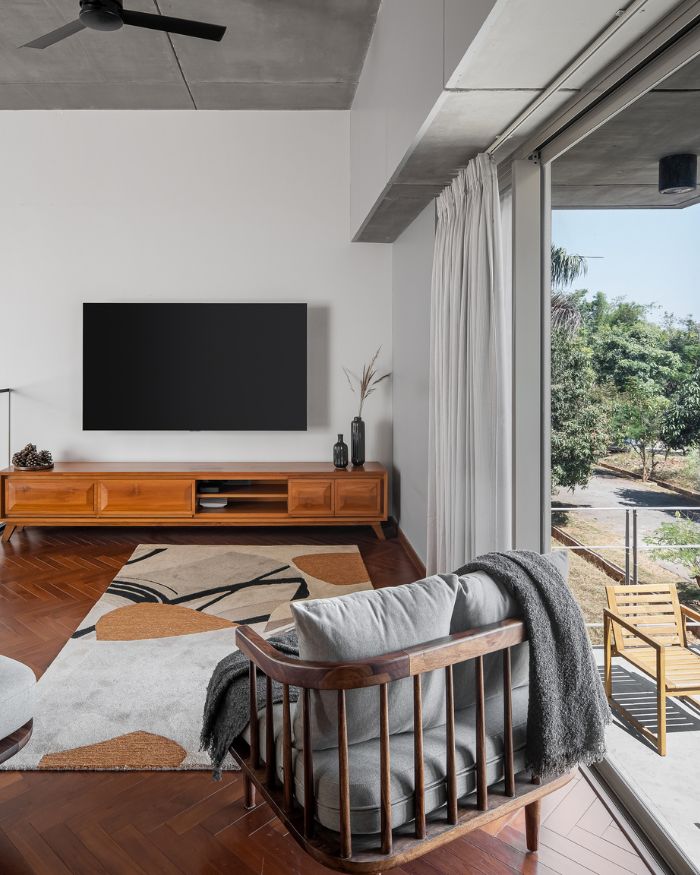 The wooden flooring is in a herringbone pattern in the family lounge. The step-down balcony leads back to the outside; Photography by Arjun Krishna