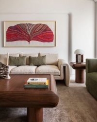 In the living room, Maitreyi Desai’s leaf-like artwork adds a gentle burst of colour, while the curved coffee table by Bombay Design Lab sits quietly at the centre, holding the space together; Art direction by Abhinit Khanna, photography by Saurabh Suryan