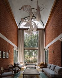 In the soaring living room, pieces from Radhika Sanghvi’s chandelier to dhurries by Enii Living and teakwood tables from Tianu sit alongside furniture from Briton and wall sconces by Olie; Photography by Ishita Sitwala